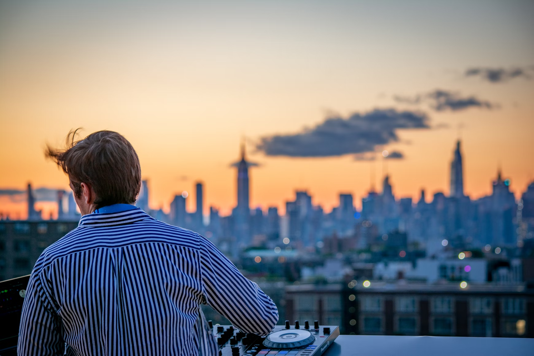 Un DJ pinchando una sesión con la ciudad al fondo