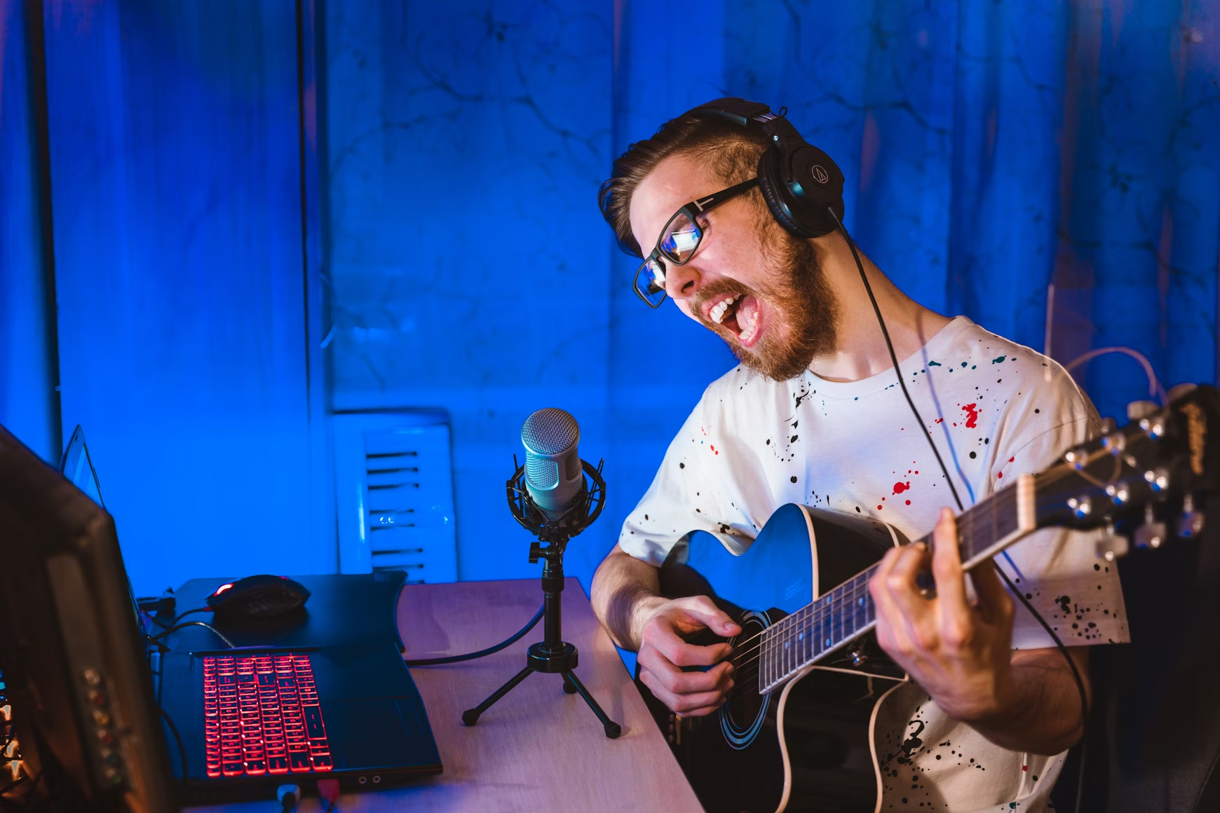 Un hombre toca la guitarra tras un escritorio.