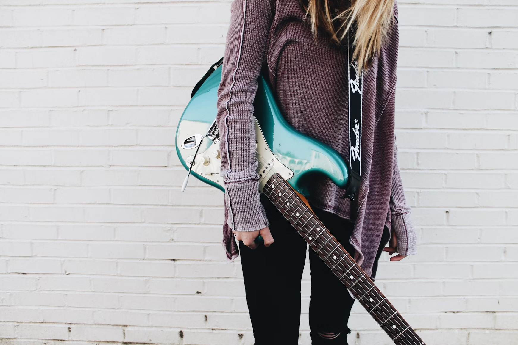 Una mujer sostiene una guitarra eléctrica.