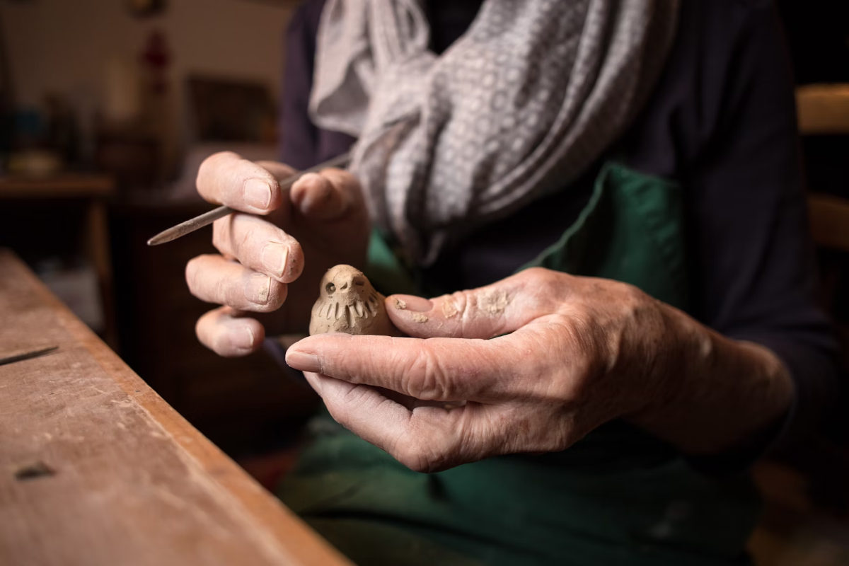 Persona tallando un pequeño pájaro de madera